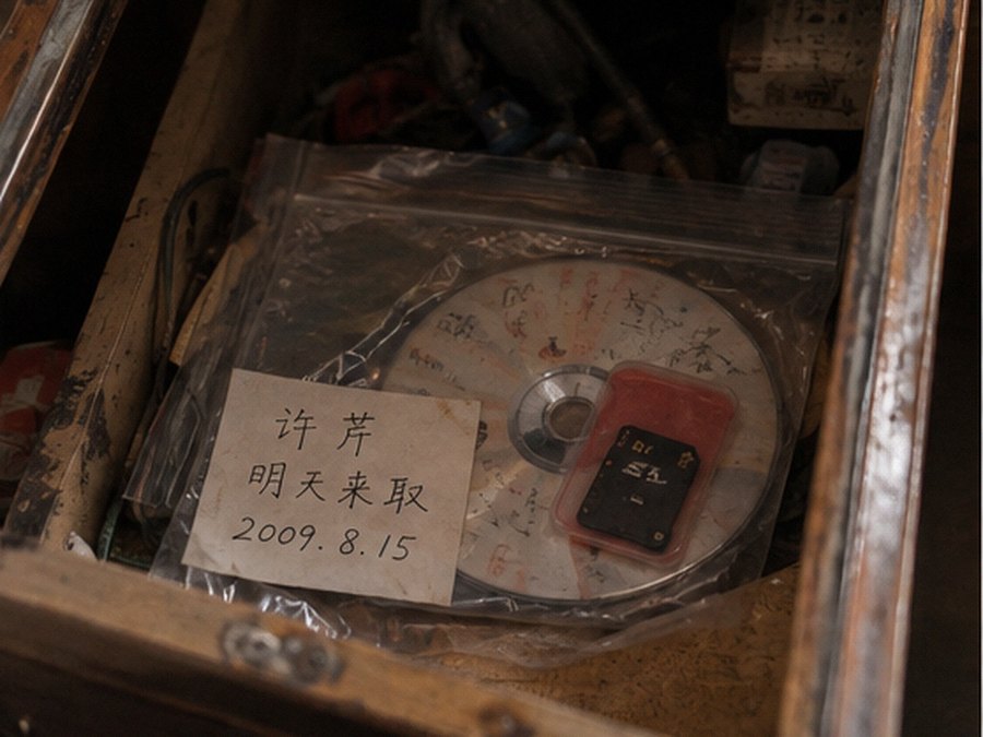 旧柜台抽屉里发现的透明袋、刻录盘、红色卡套内的SD卡和旧取件纸